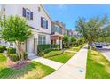Charming street view of townhomes with well-kept lawns and sidewalks, set under a clear blue sky on a sunny day at 7819 Hardenton St, Windermere, FL 34786