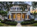 Two-story home featuring a large covered front porch, balcony, manicured landscaping, and warm lighting at 1106 Celebration Ave, Celebration, FL 34747