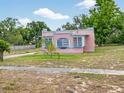 Pink single-Gathering home featuring an arched window design and small palm trees in the front yard at 16 E Orange Street St, Davenport, FL 33837