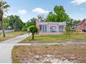 Pink house with unique window designs and a well-manicured lawn with palm trees at 16 E Orange Street St, Davenport, FL 33837