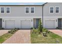 Exterior view of modern two-story townhomes featuring individual garages, brick driveways, and landscaped front yards at 16395 Bird Of Paradise Ave, Clermont, FL 34714