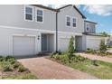 View of the front exterior of two-story townhomes with individual garages, brick driveways, and neat landscaping at 16395 Bird Of Paradise Ave, Clermont, FL 34714