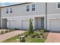 Exterior view of modern townhomes featuring individual garages, brick driveways, and landscaped front yards at 16395 Bird Of Paradise Ave, Clermont, FL 34714
