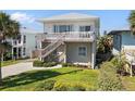 Two-story home with a light-colored exterior, complemented by a wooden staircase leading to a private upper-level balcony at 1640 N Atlantic Ave, New Smyrna Beach, FL 32169