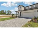 Modern two-story home featuring a large garage, covered entry, paver driveway, and beautifully manicured landscaping at 1805 Archer Dr, Minneola, FL 34715