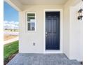 Covered front porch with a stylish door, complemented by a lantern-style light fixture and gray paver flooring at 1805 Archer Dr, Minneola, FL 34715