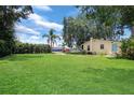 Expansive backyard with lush green lawn, mature trees, and a glimpse of the home's exterior at 200 W 27Th St, Sanford, FL 32773