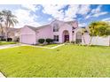 Charming pink two-story home with a well-manicured lawn and a two-car garage at 2712 Rolling Broak Dr, Orlando, FL 32837