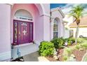 Close-up of the home's purple front door with an arched entryway and surrounding landscaping at 2712 Rolling Broak Dr, Orlando, FL 32837