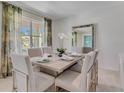 Well-lit dining room features a formal table setting with chairs, a mirror, and scenic window views at 3846 Royal Azalea Way, Sanford, FL 32773