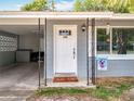 Inviting front entrance with a decorative white door, stylish overhead light fixture, and cozy carport space at 398 Rose St, Umatilla, FL 32784