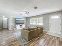 Bright living room with wood-look floors, a comfortable sofa, and a large window offering natural light at 398 Rose St, Umatilla, FL 32784