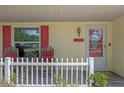 Close-up of the cozy front porch with chairs and a decorative picket fence at 5583 Miles Dr, Port Orange, FL 32127