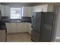 Bright kitchen features modern stainless steel refrigerator, sleek cabinetry, and a window over the sink at 7028 Clarcona Ocoee Rd., Orlando, FL 32818