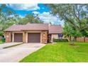 Charming home exterior featuring a well-manicured lawn, mature trees, and a two-car garage at 103 Golf Club Dr, Longwood, FL 32779