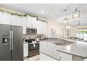 Bright, open kitchen featuring white cabinets, stainless steel appliances, and quartz countertops at 1161 Trappers Trail Loop, Davenport, FL 33896