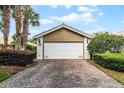 Spacious two-car garage features a brick driveway and well-manicured landscaping, offering both convenience and visual appeal at 11908 Delfina Ln, Orlando, FL 32827