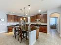 Spacious kitchen with a large island, dark wood cabinets, stainless steel appliances, and pendant lighting at 17146 Cypress Preserve Pkwy, Orlando, FL 32820