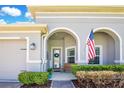 Welcoming front porch featuring an arched entryway, seating, and manicured landscaping at 1780 Southern Red Oak Ct, Ocoee, FL 34761