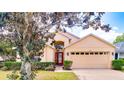 Single-story home with a well-maintained lawn, red door, two-car garage, and lush green foliage at 19756 Glen Elm Way, Orlando, FL 32833
