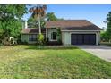 Front of single Gathering home, featuring two car garage, stone accents, mature trees, and grassy yard at 21343 Reindeer Rd, Christmas, FL 32709