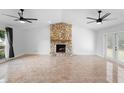 Spacious living room boasts a stone fireplace, ceiling fans, and sliding glass doors to the backyard at 21343 Reindeer Rd, Christmas, FL 32709