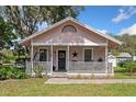 Charming pink single-story home featuring a covered porch with a swing and decorative elements at 2305 S Magnolia Ave, Sanford, FL 32771