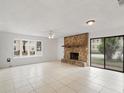 Bright living room featuring a stone fireplace, tile floors, a ceiling fan, and a large window at 445 Cottonwood Dr, Altamonte Springs, FL 32714