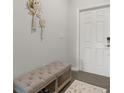 Cozy entryway with a neutral-toned bench, decorative wall hangings, and a light-colored door at 4459 Bluff Oak Loop, Kissimmee, FL 34746
