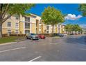 A well-maintained apartment complex with tan and white facade with ample parking and lush landscaping at 8908 Legacy Ct # 303, Kissimmee, FL 34747