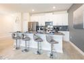 Stylish kitchen with stainless steel appliances, white cabinetry, a gray backsplash, and seating for four at 8993 Cabot Cliffs Dr, Davenport, FL 33896