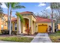 Charming single-Gathering home featuring a red tile roof, yellow garage, and mature palm trees at 1031 Marcello Blvd, Kissimmee, FL 34746
