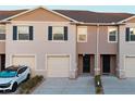 Close up of townhomes featuring garages, front doors, neutral stucco, and landscaped front yards at 1089 Blue Jay Dr, Davenport, FL 33837