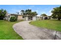 Wide shot of a single-story home with a long driveway and lush green lawn at 1108 Jordan Ave, Orlando, FL 32809