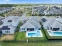 Aerial view of a home with solar panels, pool, spa, and fenced backyard in a quiet community, surrounded by lush greenery at 11927 Charades St, Orlando, FL 32832