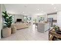 Bright, open-concept living space with tile flooring, a spacious seating area, and a modern kitchen island at 1252 Blue Daze Ln, Eustis, FL 32726