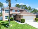 Charming two-story home featuring a well-manicured lawn, a two-car garage, and lush tropical landscaping at 140 Elgin Blvd, Davenport, FL 33897