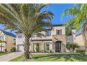 Charming two-story home featuring stone accents, a well-maintained lawn, and beautiful landscaping with mature palm trees at 15465 Heron Hideaway Cir, Winter Garden, FL 34787