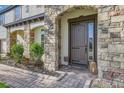 Inviting front entrance with a stone facade, arched entryway, and meticulously landscaped garden beds at 15465 Heron Hideaway Cir, Winter Garden, FL 34787