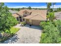 Aerial view of a well maintained one story house with a tile roof, palm trees and brick driveway at 196 Torino Ln, Kissimmee, FL 34759