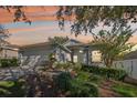 Inviting single-story home with lush landscaping, two-car garage, and picturesque sunset backdrop at 2302 Edmonton Ct, Clermont, FL 34711