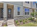 Exterior of a modern townhome featuring a stone facade, contemporary door, and well-manicured landscaping at 2382 Zaballina Pl, Kissimmee, FL 34747