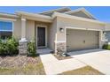 Welcoming home featuring a two-car garage, stone veneer accents, and well-kept front yard landscaping at 292 Spirit Landings Cir, Winter Haven, FL 33880