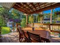 Inviting covered outdoor patio with wooden table, chairs, and lush landscaping at 302 Hermits Trl, Altamonte Springs, FL 32701