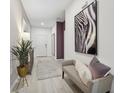 Bright hallway featuring light wood floors, a modern bench, and a striking zebra print art piece at 3588 Dahlia Dr, Haines City, FL 33844