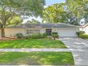 Charming single-story home with a manicured lawn, mature trees, and a concrete driveway at 4011 Teriwood Ave, Orlando, FL 32812