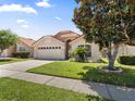 Attractive single-story home with a manicured lawn, shade tree, and a two-car garage at 5337 Watervista Dr, Orlando, FL 32821