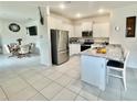 Bright kitchen featuring granite countertops, stainless steel appliances, a breakfast bar, and tile flooring at 7871 Penrose Pl, Wildwood, FL 34785