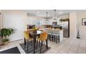 Bright kitchen featuring white cabinets, stainless steel appliances, a granite island, and a cozy dining area with stylish mustard-colored chairs at 1105 Grand Hammock Ct, Kissimmee, FL 34746