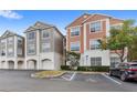 Low angle view of condo building exteriors, garages, landscaping, and accessible parking at 12843 Madison Pointe Cir # 106, Orlando, FL 32821